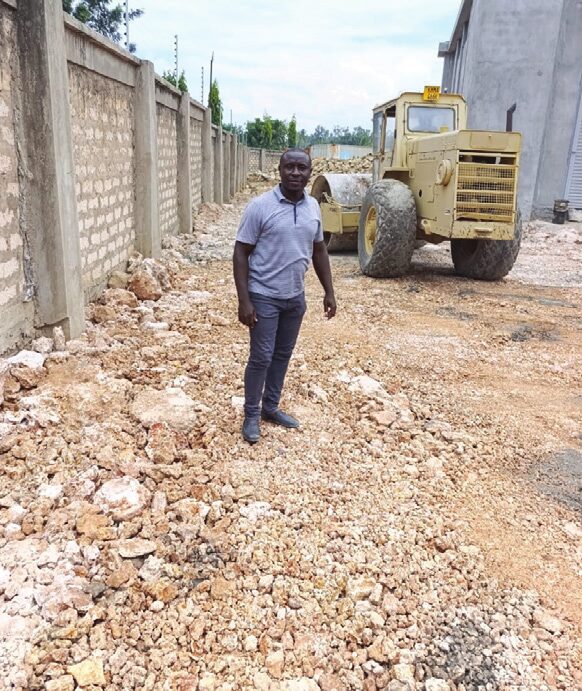 Site engineer standing on compacted ground beside a road roller